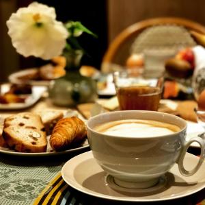 - une tasse de café assise sur une table avec des pâtisseries dans l'établissement Logis Saint-Flaceau, au Mans
