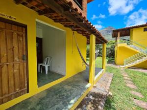 una casa amarilla con una silla en el patio en Casa da Trilha, en Vale do Capao