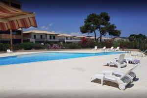 uma piscina com espreguiçadeiras brancas e uma piscina em Studio bord de mer - Piscine - Plage em San-Nicolao