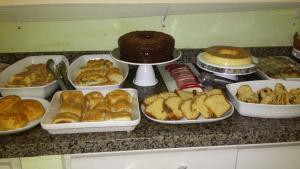 a counter with trays of pastries and cakes and cakes at Pousada Estrela do Mar Angra dos Reis in Angra dos Reis