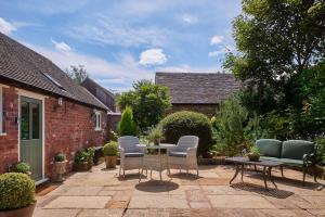 een patio met stoelen en een tafel in de tuin bij The Couple's Retreat in Ashbourne
