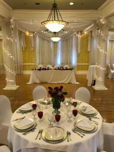 - une table dans une salle de bal avec des tables et des chaises blanches dans l'établissement Stearns Hotel, à Ludington