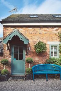 une maison en briques avec une porte bleue et un banc dans l'établissement The Old Forge, à Ashbourne