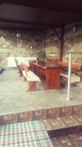 オグニャノヴォにあるGuest House Holidayの石壁前の木製テーブルとベンチ