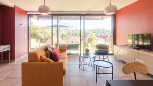 ein Wohnzimmer mit einem Sofa und einem TV in der Unterkunft 100% Relax avec Jacuzzi Privatif in Sarlat-la-Canéda
