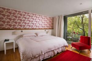 a bedroom with a large bed and a red chair at Hotel Casa Zapallar in Zapallar