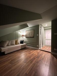 Vittorio Attic Room في تورينو: غرفة معيشة مع أريكة وأرضية خشبية