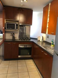 a kitchen with wooden cabinets and a microwave at America Departamentos in Santiago