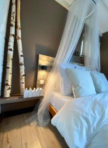 a bedroom with a canopy bed with white pillows and trees at Casa De Palmas - Tiny house in Alkmaar