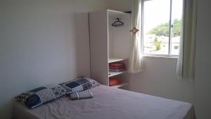 a bedroom with a bed with two pillows and a window at AP PRAIA - Cond Vog João de Góis 2 quartos com AR in Ilhéus