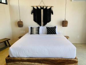 a bedroom with a bed with black and white pillows at Vida Jungle Boho Apart 13 with special fee to access Hotel Bardo in Tulum