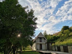 a small white house with a fence and trees at Vikendica na jezeru in Gacko