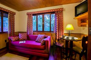 ein Wohnzimmer mit einem lila Sofa und einem Tisch in der Unterkunft Hotel Bühler in Visconde De Maua
