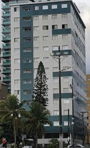 a tall building with a tree in front of it at mar e sol in Praia Grande