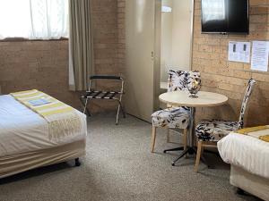 una camera con letto, tavolo e sedie di Marriott Park Motel a Nowra