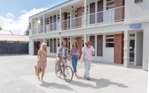 un grupo de mujeres de pie fuera de un edificio con una bicicleta en Raglan Sunset Motel and Conference Venue, en Raglan