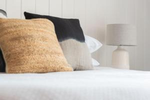 a close up of a bed with pillows and a lamp at Raglan Sunset in Raglan +48 photos