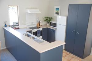 a kitchen with blue cabinets and a white refrigerator at Raglan Sunset in Raglan