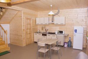 a kitchen with a table and a white refrigerator at Cottage in Sosnovom Boru in Koblevo