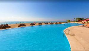 ein großer Pool neben einem Strand mit Sonnenschirmen in der Unterkunft Grand Venetian Beachfront Condos in Puerto Vallarta