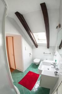 a bathroom with a white sink and a red rug at Apartments Villa Anita in Bolzano
