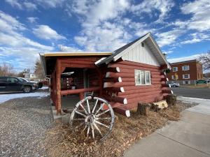 a log cabin with a wheel in front of it at Roundtop Mountain Vista - Cabins and Motel in Thermopolis