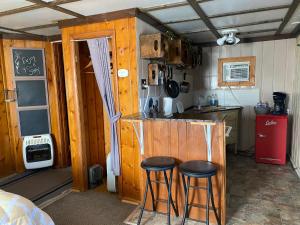 a small kitchen with two bar stools in a room at Roundtop Mountain Vista - Cabins and Motel in Thermopolis