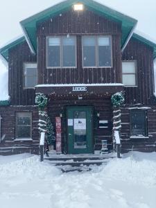 un bâtiment avec une porte verte dans la neige dans l'établissement Tug Hill Resort, à Redfield