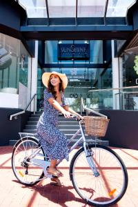 a woman in a dress and hat riding a bike at Sunshine Tower Hotel in Cairns