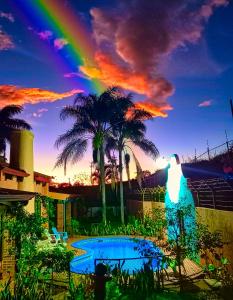 een regenboog in de lucht met een zwembad en palmbomen bij Casona del Valle in Potrerillos