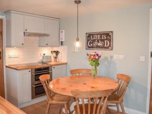 a kitchen with a table with a vase of flowers on it at Derwent Cottage in Malton