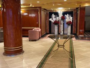 un vestíbulo con una mesa de cristal con jarrones de flores en فندق جراند كليوباترا دمنهور, en Damanhûr