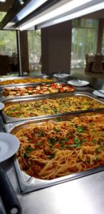 ein Buffet mit Pizzen in Tabletts mit Spaghetti in der Unterkunft Sea View Hills in Sweti Wlas