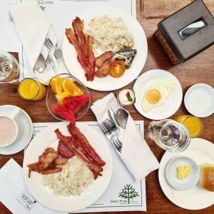 a table topped with plates of food with bacon and rice at Grand Sierra Pines Baguio in Baguio