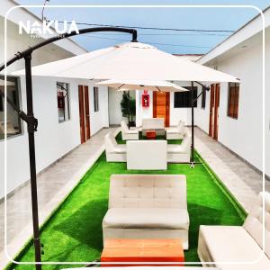 um pátio com um guarda-chuva branco e relva verde em Nakua Paracas Lodge em Paracas