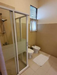 a bathroom with a glass shower and a toilet at Occazia Residence in Colombo