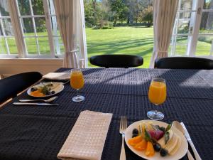 a table with a plate of fruit and two glasses of orange juice at Tipapa Estate in Scargill