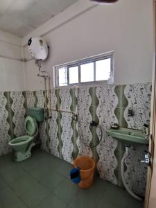 La salle de bains est pourvue de toilettes vertes et d'un lavabo. dans l'établissement Bhaskar Homestay, à Dibrugarh