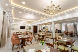 a restaurant with tables and chairs and a chandelier at Navruz Hotel Tashkent in Tashkent