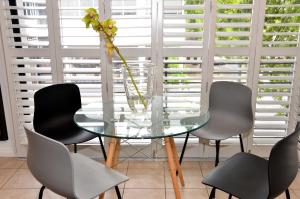 a glass table with four chairs and a vase with a flower at Concord Modern Apartment in Stellenbosch in Stellenbosch +2 photos