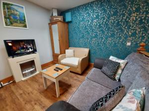 een woonkamer met een bank en een tv bij Studio Near Lyme Regis, Dog Friendly, Self Catering, Small Garden, Free Private Parking" in Axminster