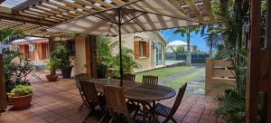 einen Holztisch mit Stühlen und einem Sonnenschirm auf einer Terrasse in der Unterkunft Villa Cap Azur in Sainte-Clotilde