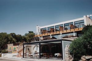 a building with a balcony with tables and chairs at Auberge Kallisté - Eco Label in Porto Pollo