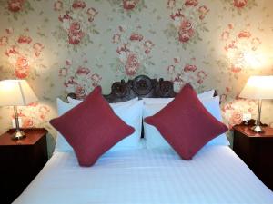 a bedroom with a bed with two red pillows at One Holyrood Hotel & Cafe in Newport