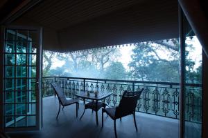 een tafel en stoelen op een balkon met uitzicht bij Coorg Wilderness Resort & Spa in Madikeri