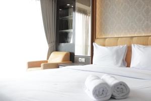 Modern Chic Studio Apartment at Tamansari La Grande near BIP By Travelio في باندونغ: غرفة فندقية بها سريرين مع مناشف عليهما +7 صور