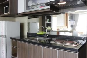 Modern Chic Studio Apartment at Tamansari La Grande near BIP By Travelio في باندونغ: مطبخ مع حوض وثلاجة