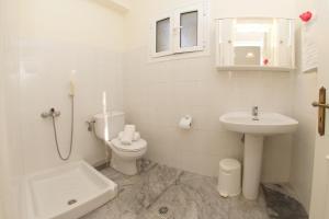 a white bathroom with a toilet and a sink at Prince Studios in Sami