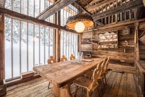 una gran mesa de madera en una habitación con ventanas en Tannhäuser Mountain Chalet, en Predoi