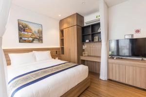 a bedroom with a large bed and a flat screen tv at CityHouse - Kim Nguyên in Ho Chi Minh City